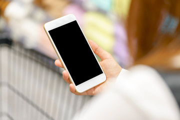 Young woman using smart phone with hands while shopping in store.