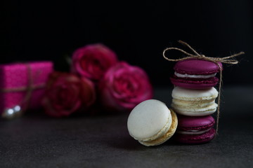 Obraz na płótnie Canvas Stack of colorful assorted french macaroons on a dark stone background. Holiday concept. Low key 