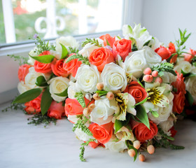 Wedding bouquet with orange and white roses on windowsill