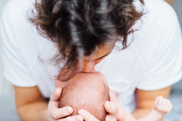 Close-up portrait of happy young father kissing his sweet adorable newborn child. Indoors shot,...