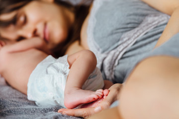 Mother with newborn baby on the bed at home.