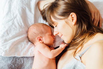 Mother with newborn baby on the bed at home.
