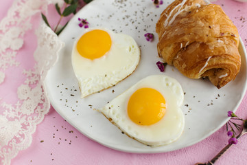 Scrambled eggs in the shape of a heart and a croissant for Breakfast (close-up)