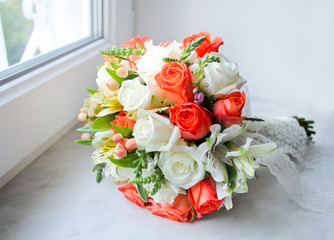 Wedding bouquet with orange and white roses on windowsill