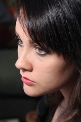 Beautiful young brunette in black, against a dark back ground