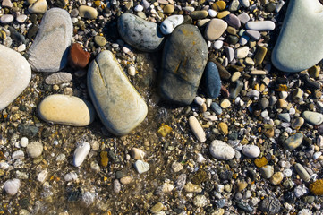 sea pebble beach with multicoloured stones, waves with foam