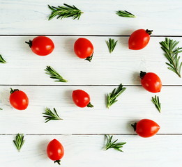 Still life with cherry tomatoes and sprigs of rosemary on white wooden background. flat lay