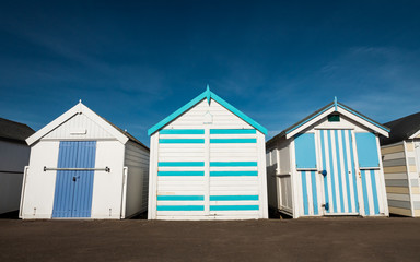 Fototapeta na wymiar Traditional English Beach Huts. A row of beach huts commonly found in British seaside resorts.