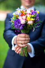 Groom hand holding wedding bouquet fresh flowers close up