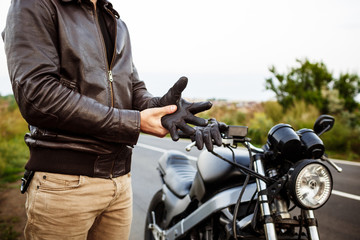 Fototapeta na wymiar Young handsome man posing near his motorbike, wearing gloves.