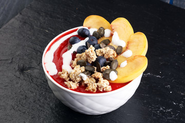 breakfast smoothie bowl with blueberries, peach and granola