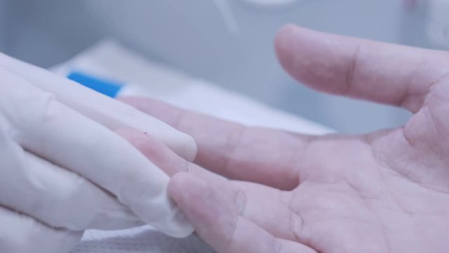 Doctor hand take blood test from patinent finger at lab. Close up of blood testing in laboratory. Lab doctor hand in gloves take finger blood test. Medical analysis. Doctor doing blood testing