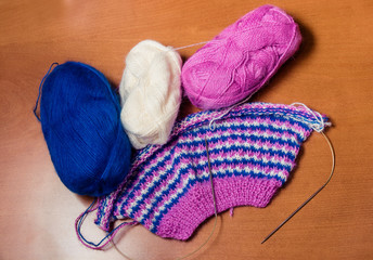 Natural woolen yarn and knitting on wooden background