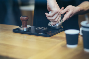 Fototapeta na wymiar Close up of barista presses ground coffee using tamper.