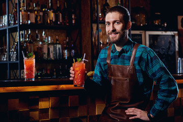 Portrait of a barman hipster with  beard smiling sitting in  bar.