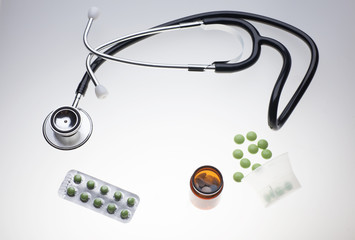 various medicine drugs and pills with stethoscope on medical light table, flat lay template, center copy-space