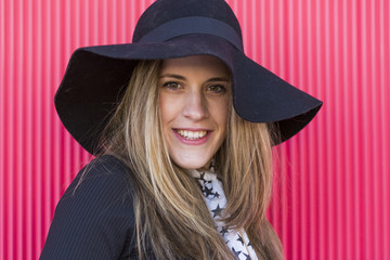 portrait of a beautiful young woman with a stylish hat, she is smiling. Red background