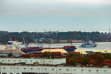 Fototapeta na wymiar Military ship sailing past the cargo port in Riga, Latvia