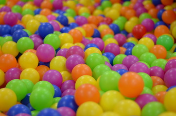 Fototapeta na wymiar The colored balls in the children's playroom. Holiday, children's party, a games room, a box filled with small colored balls, playing in ball land, ball land pattern wallpaper