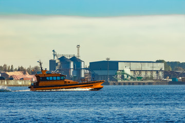 Fototapeta premium Orange pilot ship sailing past the factory in Latvia