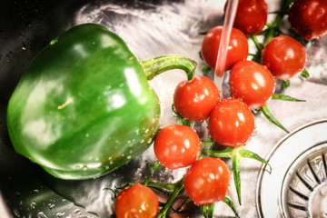 Washing cherry tomatoes and green pepper under fresh water
