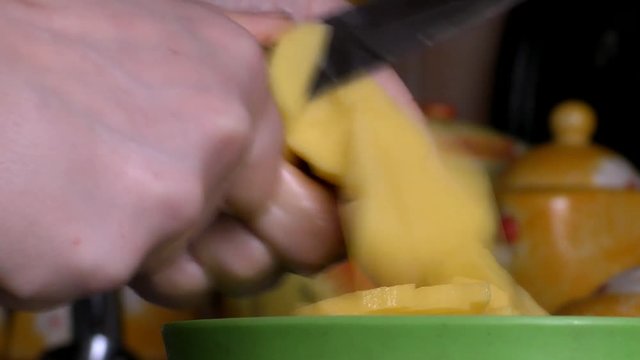 A woman is cutting a potato with a knife. Slow motion