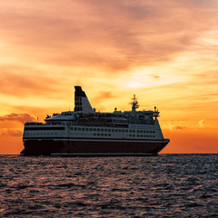 Fototapeta na wymiar Cruise liner in open sea. Passenger ferry sailing at hot sunset