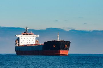 Black cargo ship moving in still Baltic sea water. Riga, Europe