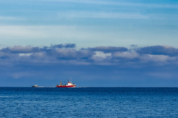 Red fishing ship sailing far in the Baltic sea. Europe