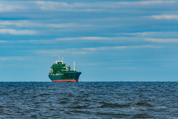 Green cargo ship moored in still Baltic sea water