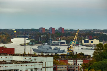 Military ship sailing past the cargo port in Riga, Latvia