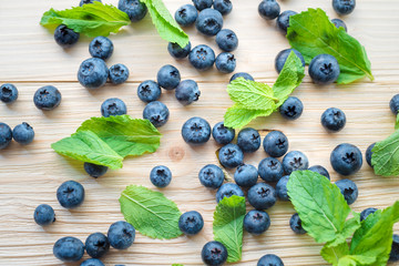 Macro photo of blueberries on a wooden table. Top view on mint leaves with blackberries. Healthy breakfast with vital vitamins.
