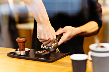 Fototapeta na wymiar View through the window of barista presses ground coffee using tamper.