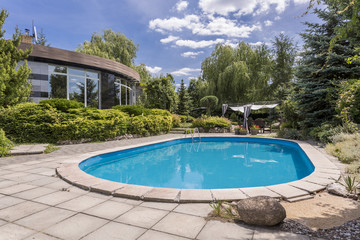 Oval swimming pool in big garden