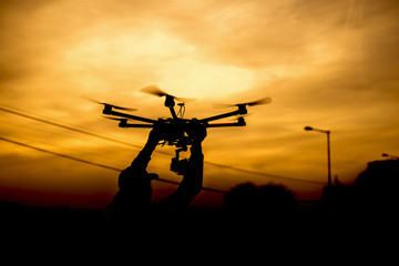 Naklejka na ściany i meble Silhouette man holding drone ready for take of background sunset.