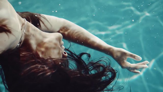beautiful young woman with long hair under water in the pool