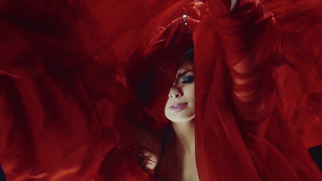 a young woman in a red dress swimming under water like in a fairy tale