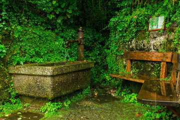 Hand pump with foutain and bench in the rain