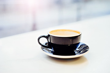 Close up of black cup on white marble countertop.