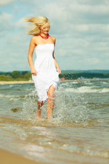 Fototapeta premium Blonde woman wearing dress walking in water