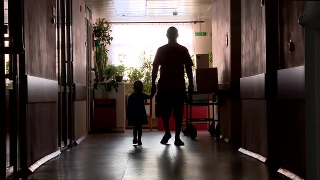 silhouette of adult and child in hospital corridor