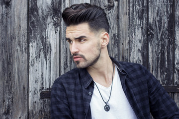 Young man posing behind wooden door