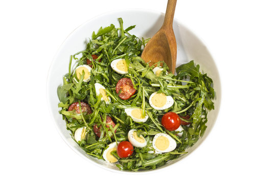 Quail eggs salad in a bowl with a wooden spoon