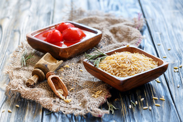 Italian pasta Orzo and tomatoes in wooden bowls.