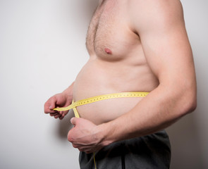 man measures the abdomen with a tape measure