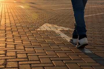 Feet on the road arrow in the rays of the setting sun