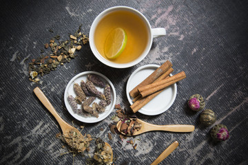 Food background with different black and green dry tea, rose buds cup of hot tea