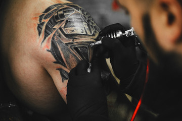 Fototapeta na wymiar the process of creating a tattoo on the back of a man