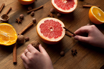 slices of oranges, lemons and grapefruits on vintage wood table. Citrus fruit with star anise, cinnamon. healthy eating with natural vitamins. holding hands.