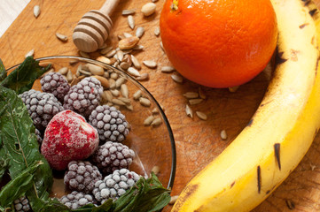 banana, orange,frozen strawberries blackberries and seeds vivid smoothie ingredients on the background